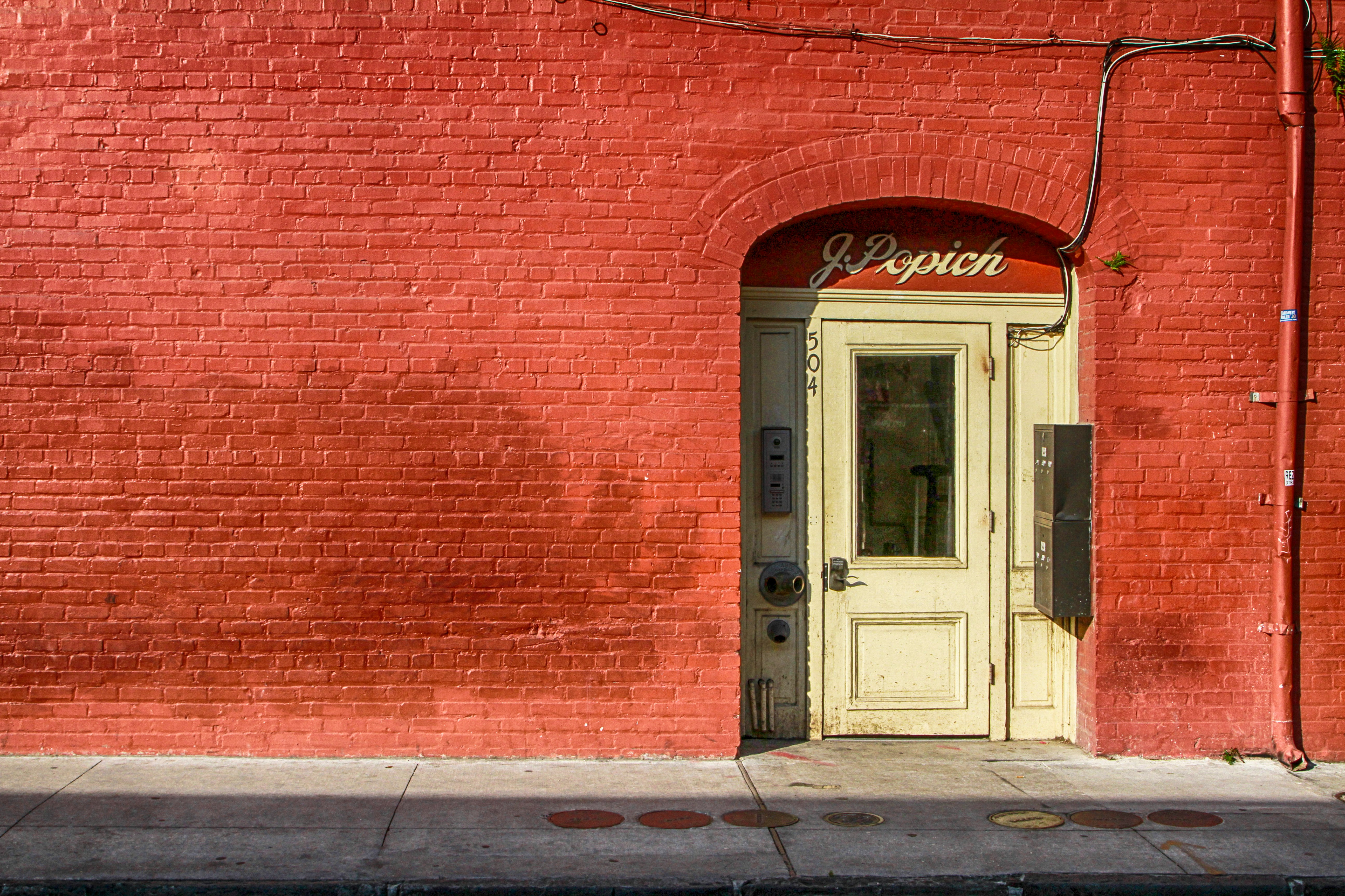 white wooden door beside red brick wall